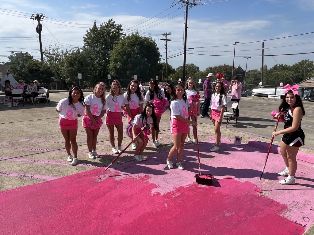 cheerleaders painting a parking space pink