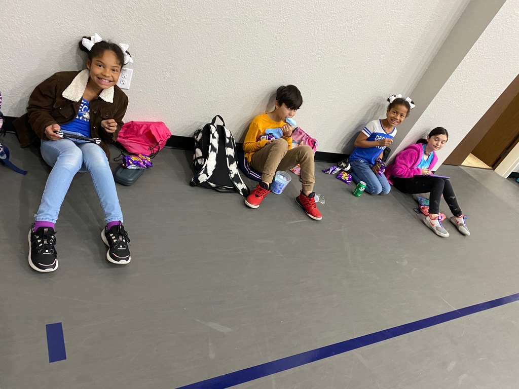 Students sitting against a wall. 