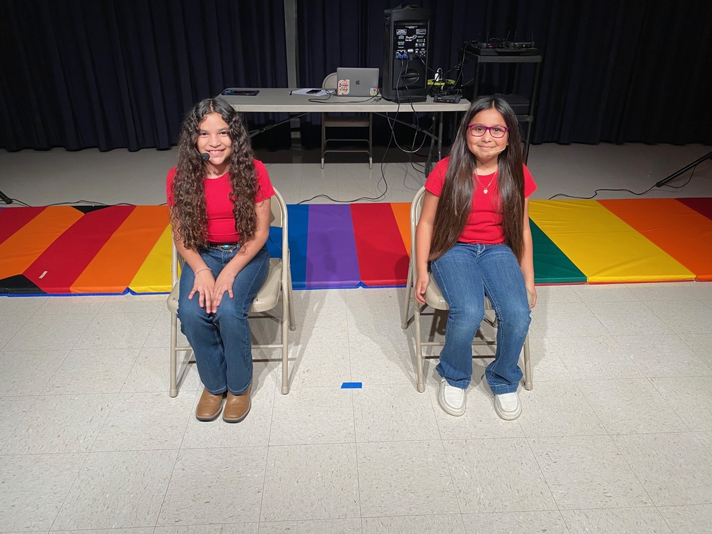 Two girls in red shirts ready to sing. 