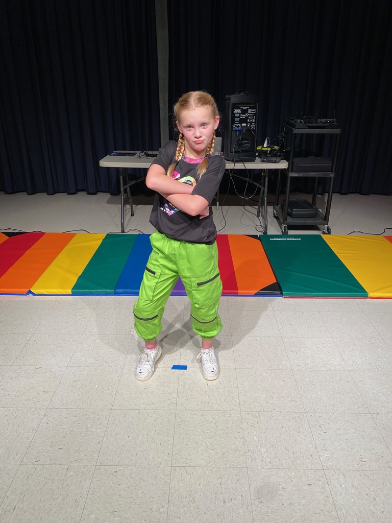 Girl in gray shirt and green pants ready to dance. 