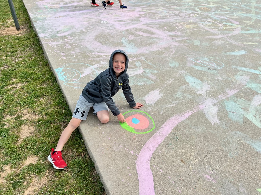 A boy drawing with chalk on the sidewalk. 