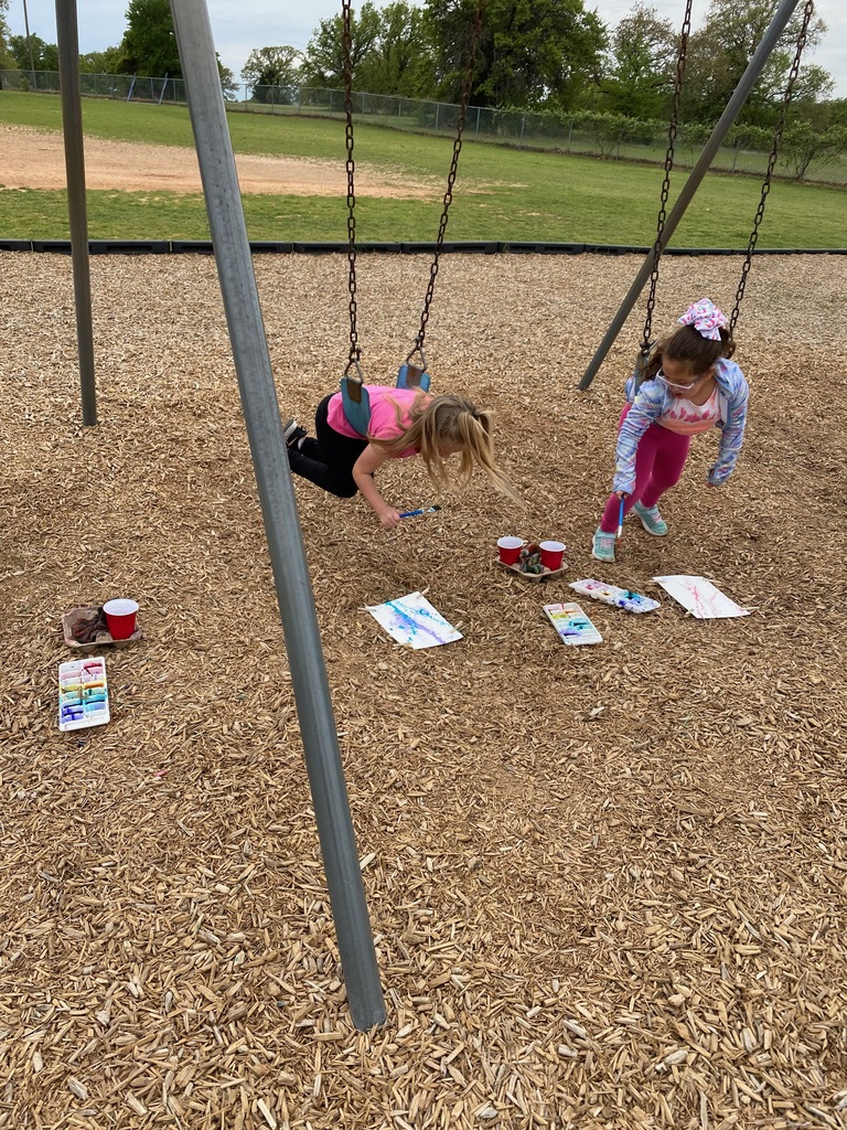 1st grade students swinging while painting with watercolor. 